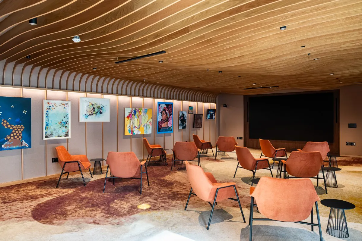 The new Delta Air Lines Foundation Community Room at Benaroya Hall, with a curved wood-slat ceiling, art wall, and lounge seating.