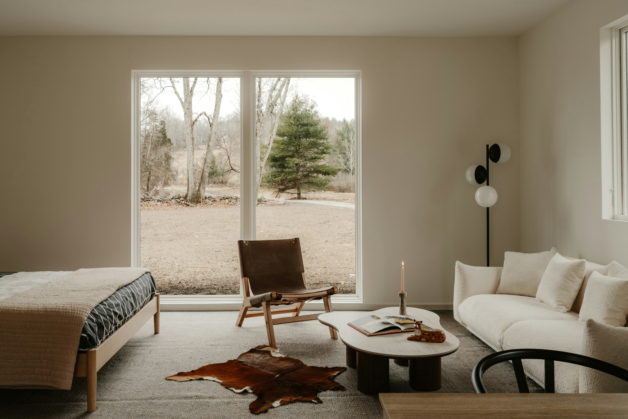 Refined living space with warm neutral furnishings, natural light and a wooded garden view